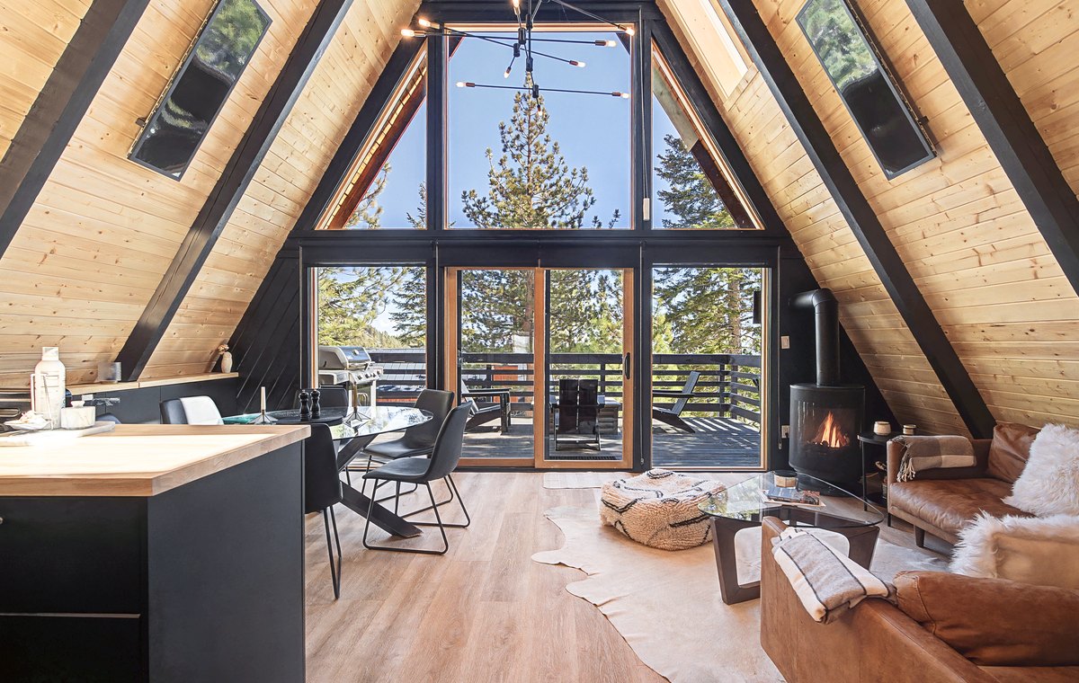 A-frame cabin living room with wood ceilings, fireplace, and mountain light.